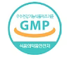 GMP-certificeringsmærke, rundt logo i turkis og hvid med tekst.
